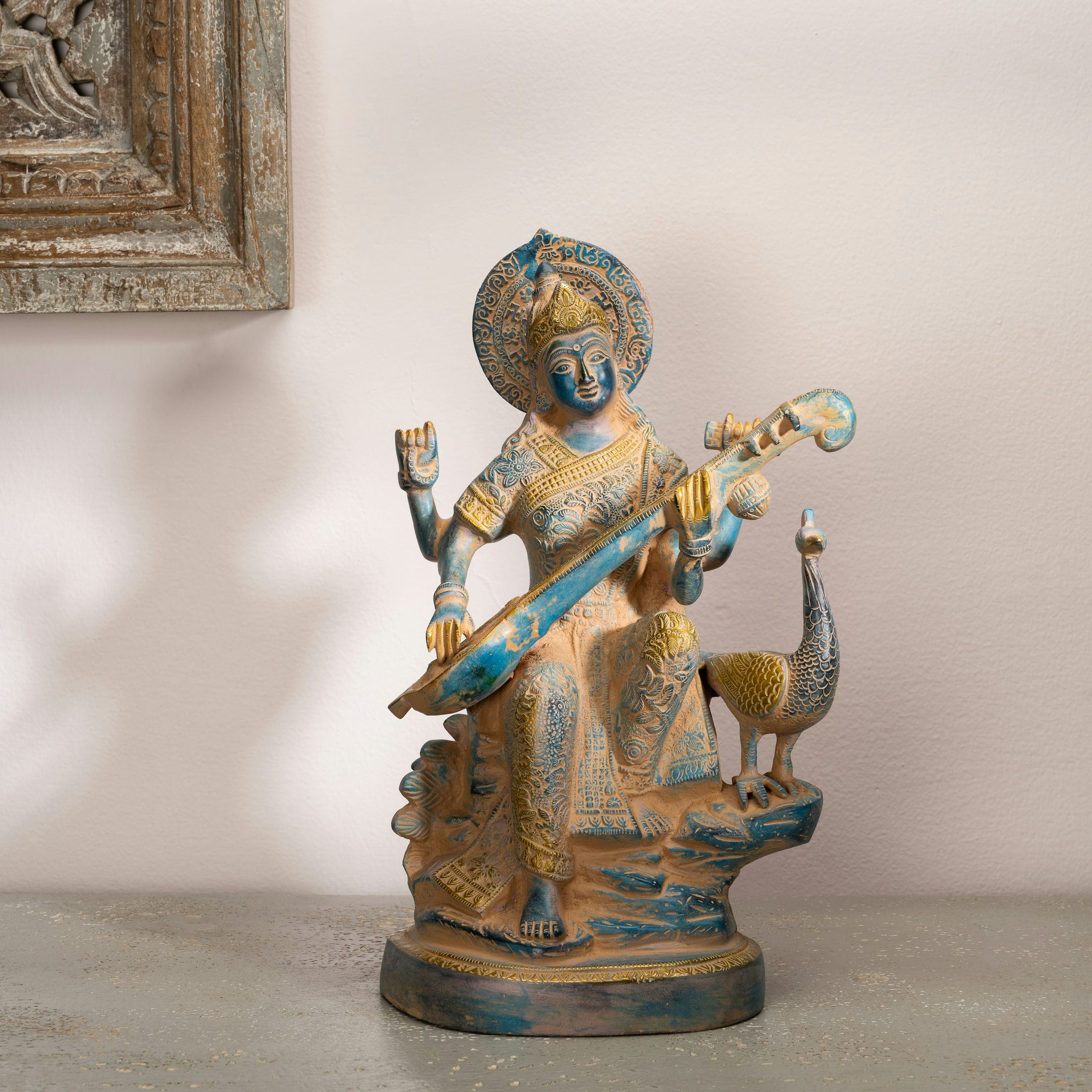 Dual-Tone Brass Saraswati Statue cradling a veena gracefully on a dedicated library console. 