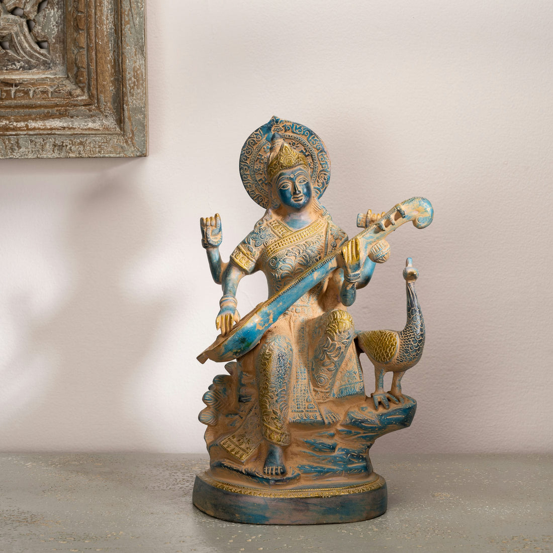 Dual-Tone Brass Saraswati Statue cradling a veena gracefully on a dedicated library console. 