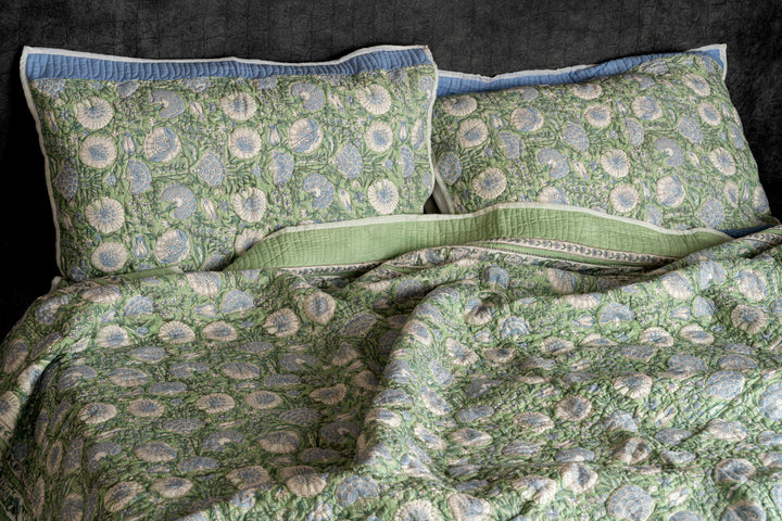 Floral block-print cotton bedcover featuring a sage green and powder blue lotus garden, styled in a sunlit master suite.