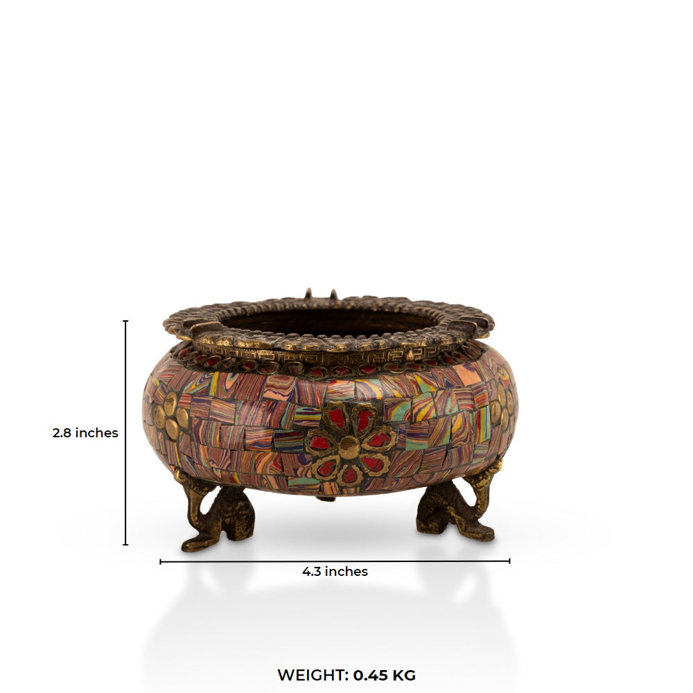 Brass Elephant Foot Mosaic Ashtray decorated with vibrant stones on a dark wood coffee table. 
